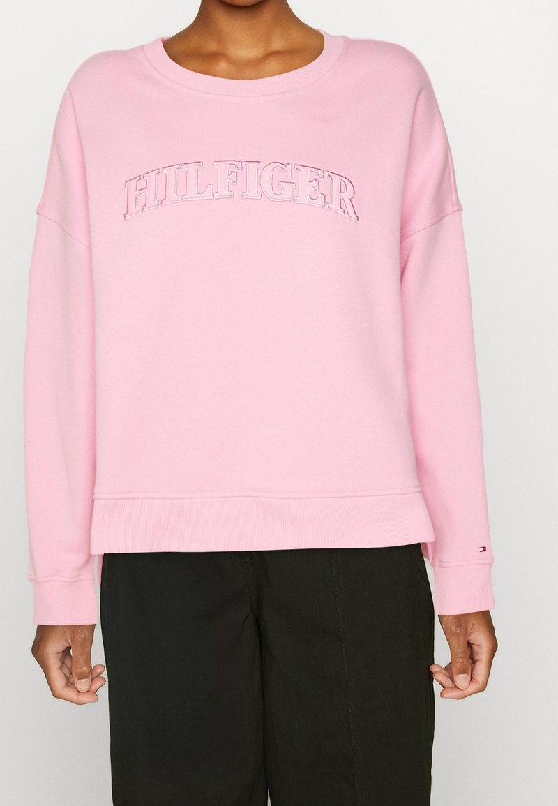 Sweat-shirt rose en mélange de coton avec encolure ronde, silhouette oversize, et logo "HILFIGER" brodé sur la poitrine.