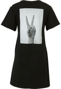 Svart t-skjorte med et stort hvitt trykk av en hånd som lager et fredstegn. Stoffet virker mykt, kortermet, avslappet passform, minimal tekstur.