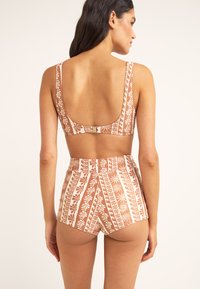 Top de bikini marrón con estampado, de espalda baja y cierre ajustable; la parte inferior de cintura alta a juego cuenta con rayas verticales y diseños florales.