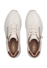Zapatillas de cuero blancas con puntera redondeada, cordones en la parte frontal y cremallera lateral. Acentos en tono marrón en el talón y el forro interior. Detalle del logo en dorado.