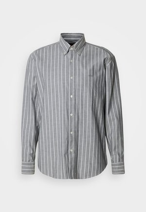 Grå skjorta med knappar framtill, vita vertikala ränder, långa ärmar och krage. Har en liten logotyp på bröstet. Tillverkad av bomull.