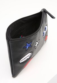 Czarna skórzana saszetka na zamek, ozdobiona haftowanymi oczami, gwiazdkami oraz dymkiem z napisem „meow!” białym tekstem.