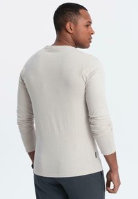 Beige blouse met lange mouwen en een ronde hals, met een gladde textuur, fitted mouwen en een rechte onderzoom.