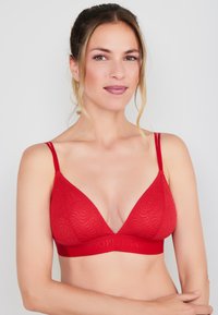 Rode naadloze driehoek bralette met dunne verstelbare bandjes. Heeft een textuur golfpatroon en een stevige band met de opdruk "JOOP! JEANS."