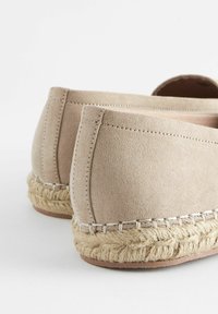 Beige suède espadrilles met een gevlochten jute middenzool en gestikte accenten; afgeronde achterkant met een soepele textuur en een minimalistisch ontwerp.