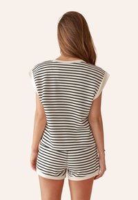 Gestreiftes zweiteiliges Lounge-Set in Creme und Schwarz, bestehend aus einem Oberteil mit kurzen Ärmeln und Shorts, mit relaxed Fit und weich strukturiertem Stoff.