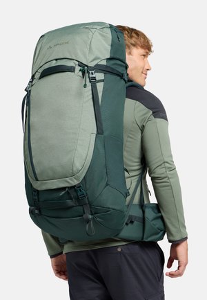Zaino da trekking verde realizzato in tessuto resistente, con una parte frontale strutturata, spallacci regolabili e una cintura in vita imbottita per un maggiore supporto.
