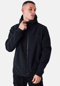 Felpa nera con zip, realizzata in tessuto morbido, con colletto alto, che presenta un logo sul petto e tasche laterali. Design semplice ed elegante.