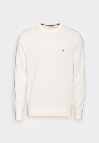 Maglione crema con scollo rotondo, maniche lunghe e un piccolo logo nero sul petto. Tessuto morbido, polsini e orlo a costine.