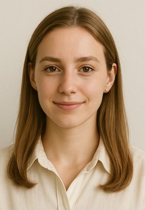 Portrait einer Person mit langen braunen Haaren und braunen Augen, die ein hellbeiges Hemd mit Kragen trägt, vor einem neutralen Hintergrund.