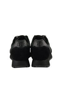 Scarpe sportive nere realizzate con un mix di materiali, tra cui suede e pelle sintetica, con "1968" impresso sul tallone.
