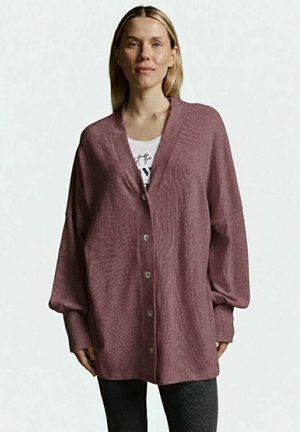 Oversized maroon cardigan with a textured surface, v-neckline, button closures, and long, dropped sleeves. Worn over a white shirt.