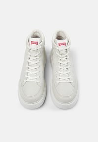 Zapatillas altas de piel blanca con una textura suave, con cordones planos y una etiqueta de logo roja en la lengüeta. Punta redondeada y cuello acolchado.
