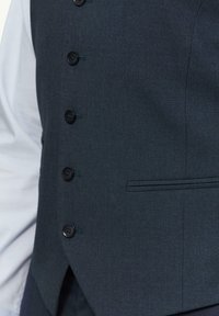 Navyblauw vest met een gestructureerde stof, voorzien van zes zwarte knopen en een zijzak. Het ontwerp is slim fit met een scherpe snit.