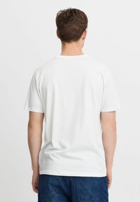 Hvid bomulds T-shirt med korte ærmer og rund halsudskæring. Bagsiden har en glat tekstur uden synlige logoer eller mønstre.