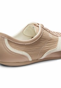 Baskets beige clair en cuir lisse avec des accents texturés. Présentent un détail en daim blanc et une fermeture à lacets simple. Semelle en caoutchouc.