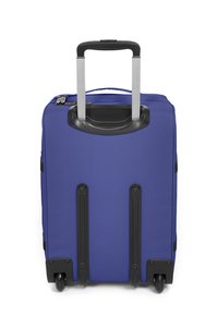 Blå tygväska med ett utdragbart silverhandtag, svarta accenter, fyrhjulig och med dragkedjor. Har en slät yta och rektangulär form.