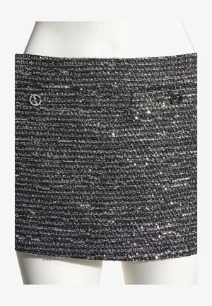 Minigonna nera texturizzata con costine orizzontali e piccoli paillettes lucidi, con due bottoni metallici rotondi vicino alla vita.