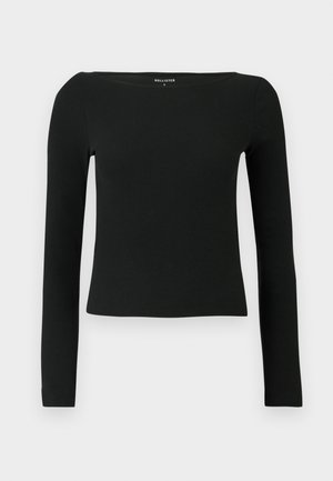 Czarny longsleeve z dekoltem w łódke, wykonany z prążkowanego materiału. Charakteryzuje się dopasowanym krojem i minimalistycznym stylem, bez widocznych elementów metalowych czy wzorów.