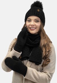 Cappello di maglia nera con pon-pon, guanti e sciarpa coordinati, tutti con motivi strutturati. Tessuto caldo, accogliente e morbido.