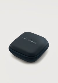 Συμπαγές μαύρο θήκη με φερμουάρ και το λογότυπο Tommy Hilfiger σε λευκό και κόκκινο στο κέντρο πάνω, σχεδιασμένη για αποθήκευση φορητών αντικειμένων.