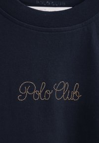 Camiseta de algodón azul marino con cuello redondo y "Polo Club" en acentos dorados punteados. Textura suave con detalles de diseño mínimos.