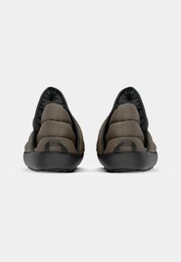 Brune puffer-stil slip-on sko med avrundet bakside, svart gummisåle og tekstildetaljer, med en glatt tekstur og minimalistisk design.