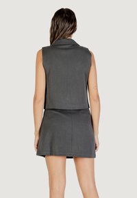 Completo grigio in due pezzi con top smanicato con colletto e gonna aderente. Il tessuto ha una texture liscia e un design sartoriale.