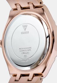 Zadnja stranica rosegold Guess urice, ki prikazuje ohišje iz nerjavečega jekla z oznako vodoodpornosti in modelno številko GV1031213.