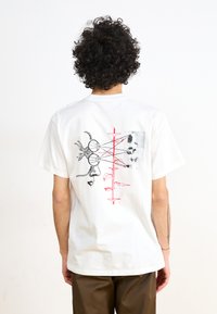 Hvit bomulls t-skjorte med et grafisk design på baksiden med abstrakte former, røde detaljer og svart linjekunst. Løs passform, kortermet.