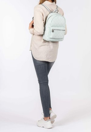 Jasnoniebieski pikowany plecak z zamykaną na zamek kieszenią z przodu oraz regulowanymi paskami, wykonany z materiału syntetycznego, prezentowany na osobie.