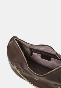 Borsa a mano in pelle marrone con zip dorata e tracolla a catena, aperta per mostrare l'interno foderato in tessuto con marchio e tasca interna con zip.