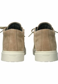 Zapatos de ante beige con punta redonda, perfil bajo y suela de goma blanca. Incluyen cordones y un forro interior suave.