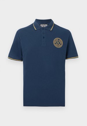 Marineblå kortermet poloshorte med gullkant på krage og ermer, tre knapper, og rund Versace Jeans Couture-logo på brystet.