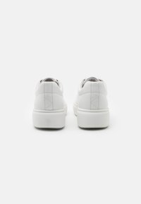 Sneakers bianchi in pelle con una texture liscia, caratterizzati da una punta arrotondata e una spessa suola in gomma bianca; dettagli di cucitura ridotti nella parte posteriore.