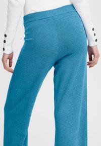 Blauwe wijde broek gemaakt van zachte stof, met een geribde tailleband. Zichtbare stiksels en een naadloos ontwerp verhogen het comfort.