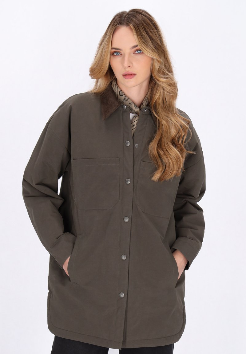 Giacca verde oliva con colletto a camicia, due tasche frontali e bottoni metallici. Il tessuto appare morbido con una finitura leggermente texturizzata.