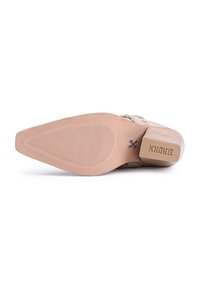 Zapato de tacón alto beige con punta afilada y superficie texturizada. La suela es lisa con detalles acanalados y un tacón de madera cuadrado.