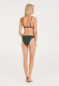 Donkergroene bikini met dunne verstelbare bandjes en een geribbelde textuur. De onderkant heeft een gematigde bedekking en een naadloos ontwerp.