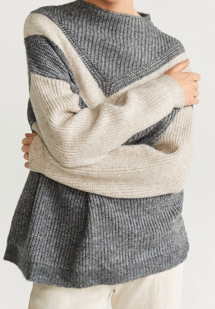 Pull en tricot avec un design en blocs de couleur gris et crème, texture côtelée et col montant. Coupe ample avec des manches longues.