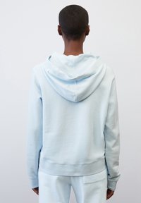 Felpa leggera blu chiaro realizzata in morbido tessuto texture, con un cappuccio ampio, polsini a coste e una vestibilità rilassata, mostrata da dietro.