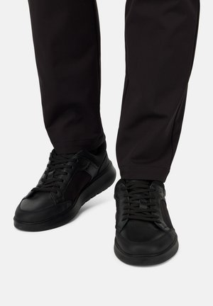 Sneaker nere con un design in pelle testurizzata e mesh, caratterizzate da una punta rotonda, chiusura con lacci e una suola spessa e imbottita.