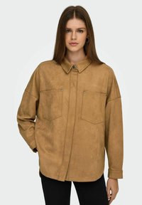 Tan faux suede overshirt met een kraag, twee borstzakken, drukknopen en lange mouwen, met een ontspannen pasvorm en zachte textuur.