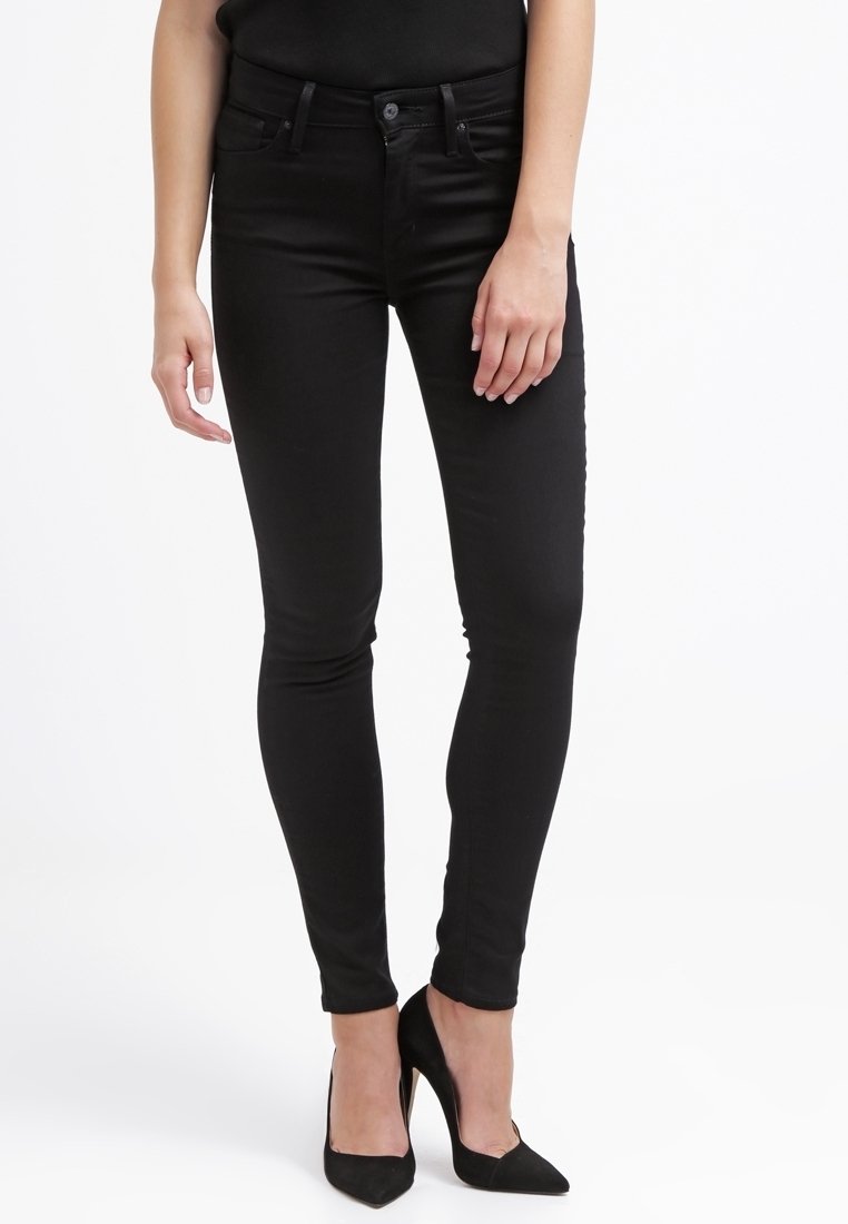 Jeans skinny negros hechos de denim con un diseño clásico de cinco bolsillos, que incluyen trabillas para cinturón y una textura mate sutil.