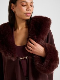 Burgundiikarva kraega siidise tekstuuri ja kuldse riistvaraga paelaga. Elegantsete pika varrukaga karvase mansetiga.