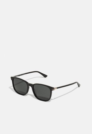 Black rectangular sunglasses with dark lenses, plastic frame, and gold accents on the hinges. Sleek design with straight arms.