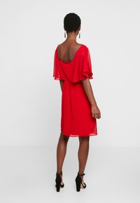 Robe rouge à manches courtes, avec une coupe ample et un dos dégagé. Fabriquée en tissu léger, elle possède une taille froncée et tombe au-dessus du genou.