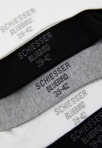Vier Paar Socken in Weiß, Schwarz und Grau, mit gestrickter Textur und Größe sowie Logo auf jedem Paar gedruckt.