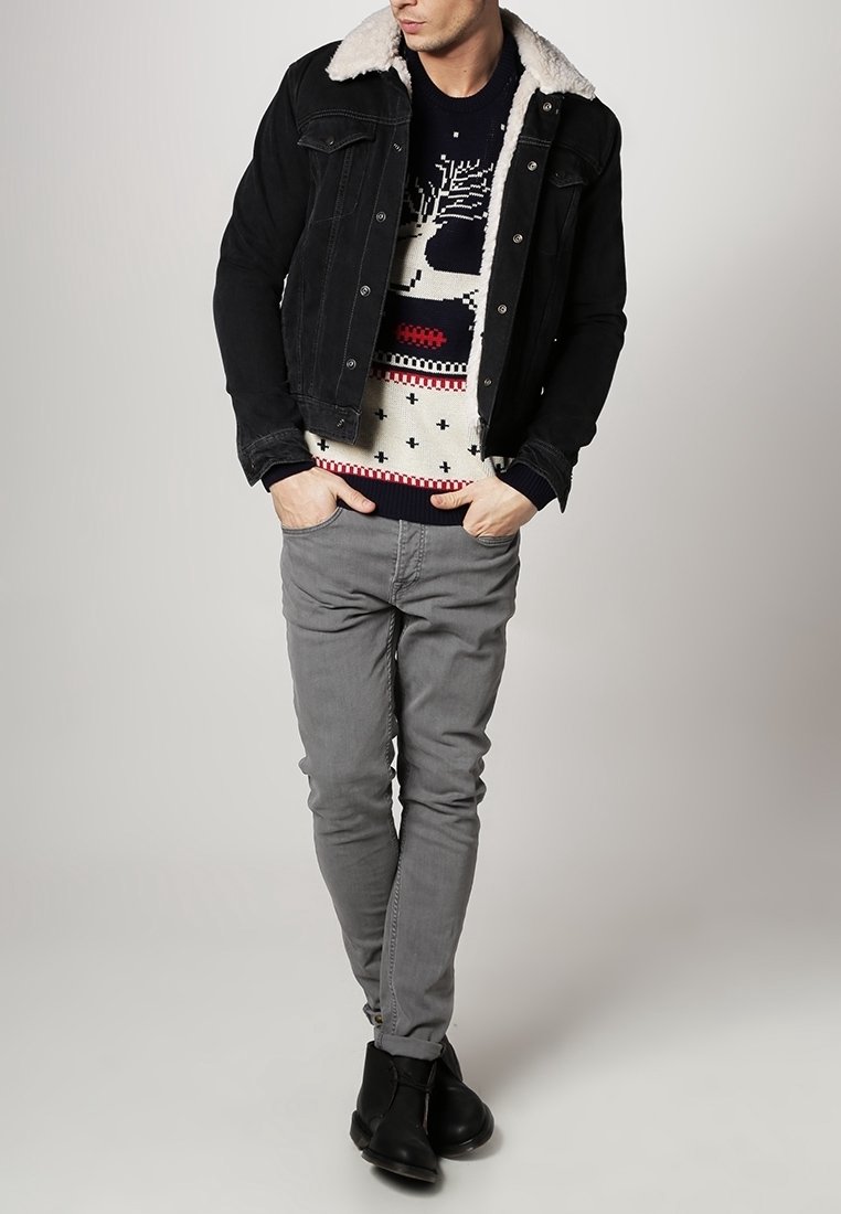 Svart denimjacka med krage av konstpäls, mönstrad gräddfärgad tröja, grå slim fit-byxor och svarta ankelboots. Enkel, avslappnad outfit.