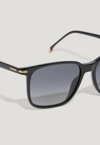 Gafas de sol rectangulares negras con lentes grises degradados. Presentan detalles dorados y un diseño elegante y minimalista con patillas con punta rosa.